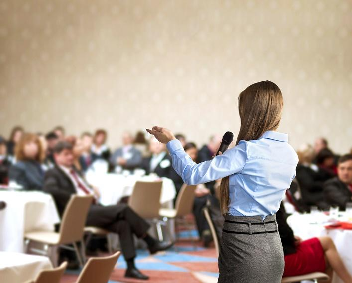 A person standing in front of a group of people sitting in chairs 
Description automatically generated with medium confidence